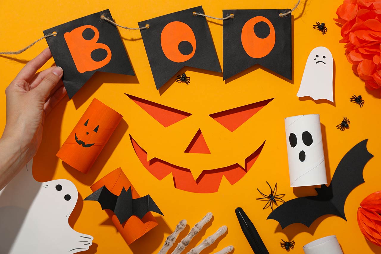 Paper decorations for Halloween on orange background, top view