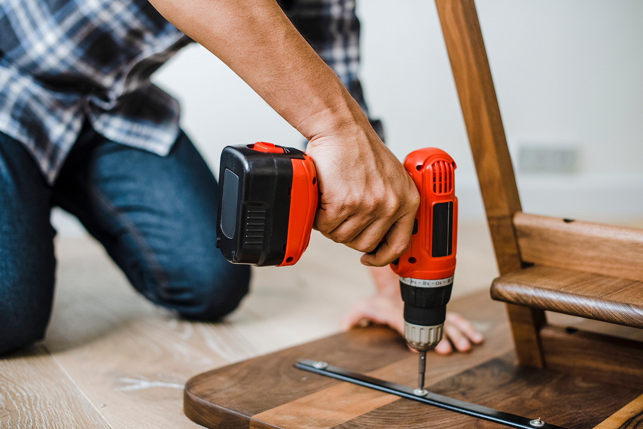 Man using hand drill to assemble a wooden table